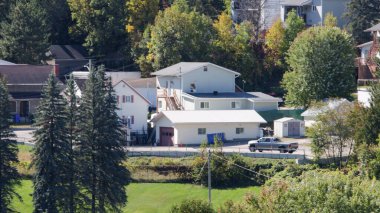 Kanada, 20 Eylül 2025: Sonbahar ağaçları ve park halindeki gümüş kamyonlarla çevrili banliyö evleri