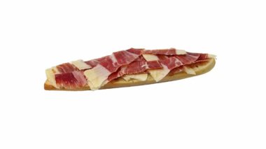 Bir dilim ekmek üzerinde dilimlenmiş İber jambonu (jamn serrano), dönen, beyaz arka planda izole edilmiş.