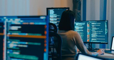 Genç Asya 'lı kadın bağımsız gözlük daktilo yazma işlemi akıllı program göçebe, video oyunu, kodlama dili, tasarımcı, gece ofisindeki masaüstü bilgisayarında büyük veri merkezi.