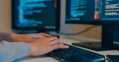 Kapalı genç yetişkin Asya kadın serbest yazma komut AI bot uygulama programı göçebe, video oyunu, kodlama dili, tasarımcı, gece ofisindeki masaüstü bilgisayarında büyük veri merkezi.