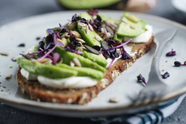 Toast with avocado on plate on grey background. Closeup