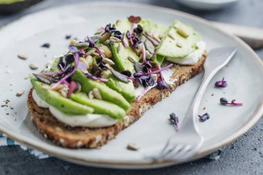 Toast with avocado on plate on grey background. Closeup