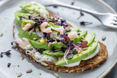 Toast with avocado on plate on grey background. Closeup