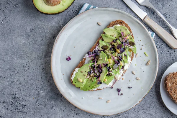 Toast with avocado on plate on grey background. Closeup