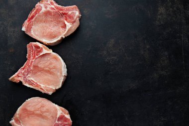 Raw meat pieces on dark backrgound. View from above with copy space. 