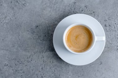 Espresso cup with coffee in white ceramic cup on grey background. Top View. 