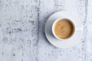 Espresso cup with coffee in white ceramic cup on grey background. Top View. 