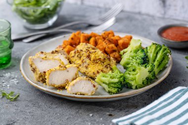 Grilled chicken breast on plate with vegetables on table. 