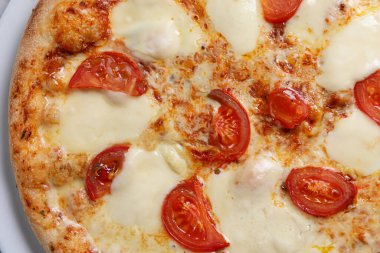 Eritilmiş peynirli ve taze domatesli klasik İtalyan pizzası. Basit, lezzetli ve her menü veya teslimat servisi için mükemmel.