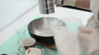 Kadın evde hamur tatlısı için maya ekliyor.