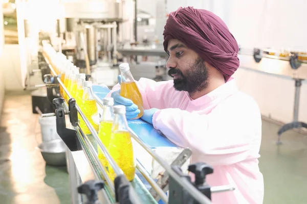 South Asia male factory worker or man expert quality staff is checking bottles line for beverage