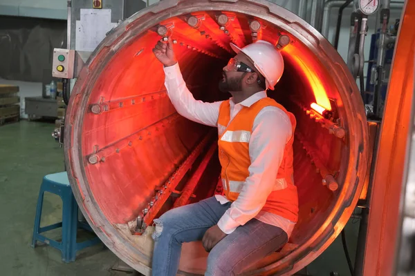 South asia male factory worker or Man engineer or expert staff wear safety vest and helmet of maintenance and checking steam boiler