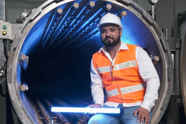 South asia male factory worker or man engineer or expert staff wear safety vest and helmet of maintenance and checking steam boiler with UV cleaning