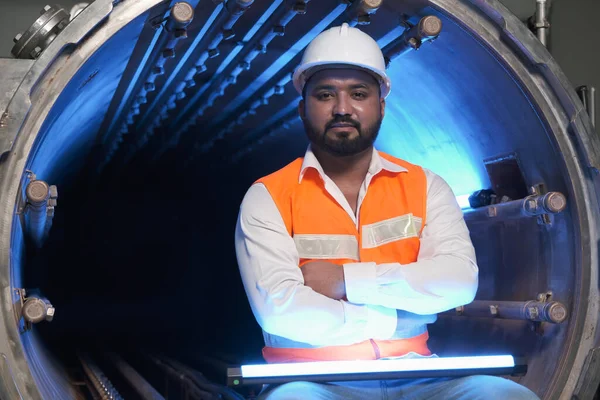 South asia male factory worker or man engineer or expert staff wear safety vest and helmet of maintenance and checking steam boiler with UV cleaning