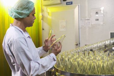 Güney Asya 'da üst düzey erkek fabrika işçisi veya uzman personel içki kuyruklarını kontrol ediyor.