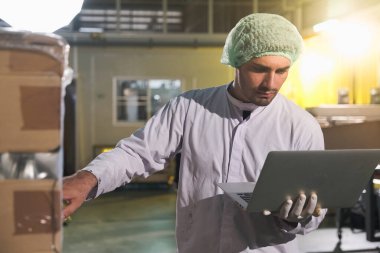 Güney Asya erkek fabrika işçisi veya uzman personel stokları kontrol ediyor ve dizüstü bilgisayarı ellerinde tutuyorlar