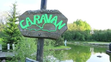 Göl kenarında yeşil karavan simgesi olan tahta tabela - Kamp ve Seyahat Kavramı