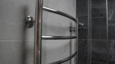 Projelerinize, güzel gri fayanslı bir banyoya yerleştirilmiş yeni bir krom havlu ısıtıcısının yüksek çözünürlüklü videosuyla modern tarz bir dokunuş ekleyin. Görüntülerde parlak bir krom kaplama var.
