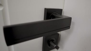Bu yüksek çözünürlüklü yakın çekim videosuyla projelerinize sofistike bir kontrastlık ekleyin. Görüntülerde parlak siyah bir kapı kolu ve beyaz bir banyo kapısı var.