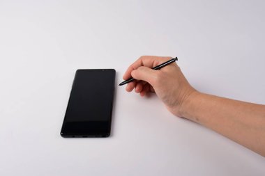 Beyaz arkaplana izole edilmiş yazmak için elinde kalem, akıllı telefon ve siyah stil. 
