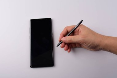 Beyaz arkaplana izole edilmiş yazmak için elinde kalem, akıllı telefon ve siyah stil. 