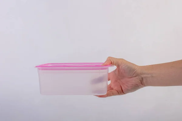 Pink plastic food container in hand isolated on white background.