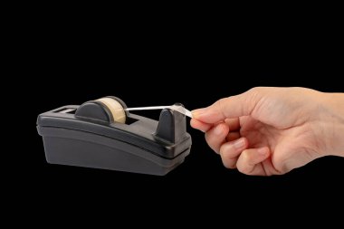 Hand and office stationary scotch tape dispenser isolate on black background. 