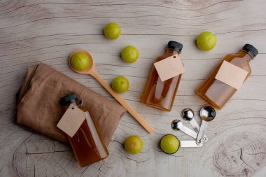 Closeup pile of fresh green Amla or Indian gooseberry fruits (phyllanthus emblica) with Gooseberry Juice, healthy diet on wood table.