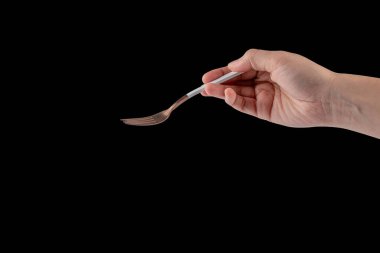 Hand and metal white fork on black background