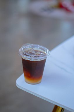 Black coffee, Americano coffee in plastic coffee cup on white table in coffee shop.