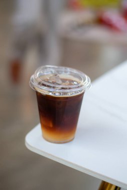 Black coffee, Americano coffee in plastic coffee cup on white table in coffee shop.