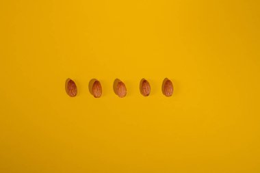 Sarı arkaplanda izole edilmiş badem tohumları