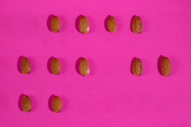 Pembe arka planda izole edilmiş badem tohumları