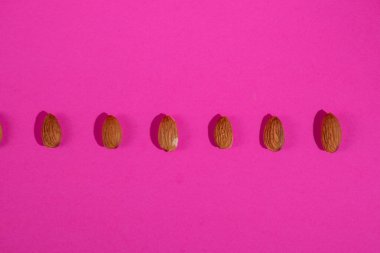 Pembe arka planda izole edilmiş badem tohumları