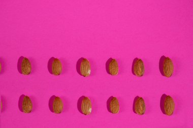 Pembe arka planda izole edilmiş badem tohumları