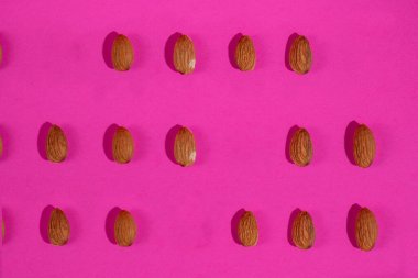 Pembe arka planda izole edilmiş badem tohumları