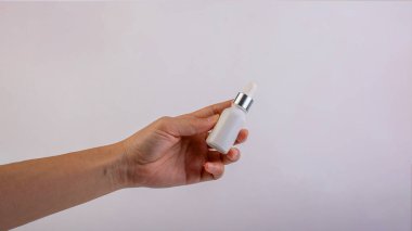 Kadın eli kozmetik ürünleri beyaz arka planda tüpte, şişede, losyonda veya serumda tutuyor..