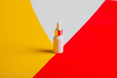 Sarı ve kırmızı ve beyaz arka planda tüp, şişe, losyon veya serumda kozmetik ürünler.