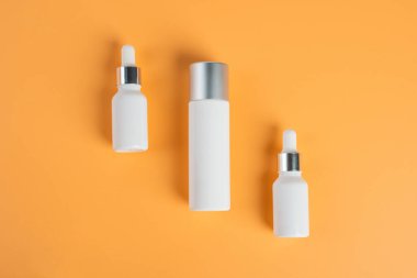 Krem arka planda tüp, şişe, losyon veya serum gibi kozmetik ürünler. 