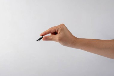 Beyaz arka planda elinde siyah bir vida.