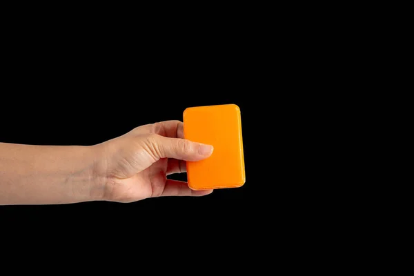 Hand and orange soap on black background