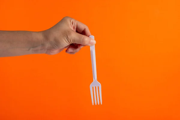 Turuncu arka planda beyaz plastik çatal