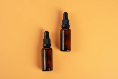 Krema arka planında koyu kehribar camından yapılmış kozmetik şişeler.