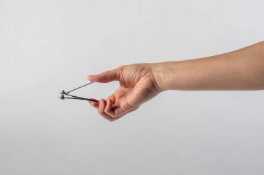 El ele tutuşan tırnak makası beyaz arka planda izole edilmiş..