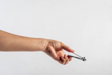 El ele tutuşan tırnak makası beyaz arka planda izole edilmiş..