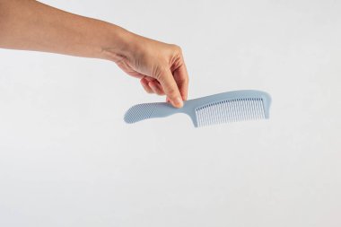 Yeni mavi saç tarağı ve el beyaza izole edilmiş..