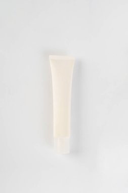 Krem veya losyon için plastik beyaz tüp. Pembe arka planda cilt bakımı veya güneş kremi kozmetiği.