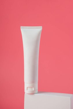 Krem veya losyon için plastik beyaz tüp. Cilt bakımı ya da pembe arka planda şık dekorları olan güneş kremi kozmetiği.