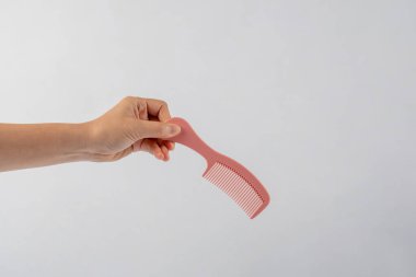 Eldeki pembe saç tarağı beyaz arkaplanda izole edildi