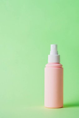 Yeşil arka planda kozmetik pembe şişe, şişe, losyon ya da serum.. 